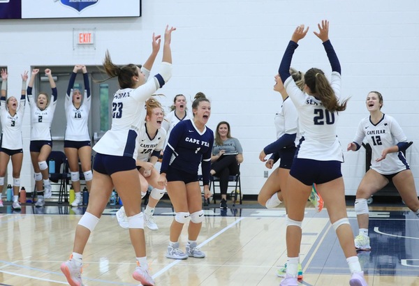 CFCC Volleyball players cheering and celebrating in a group after a scored point on the court