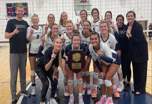 photo of CFCC Volleyball team with District Championship trophy. Top row left to right: Jeff Y. (Coach), Mary Moore, 	Madalyn Rinck, Madie Ballou, Isa Yedo, Nora Pit, Alecia R. (Coach), Colby Rosser (Coach). Middle row left to right: Charly Meade, Kara Walker, London Ipsen, Hannah McDowell. Front row left to right: Jodee Barnes, Leah Davis, Abby Vendemia.